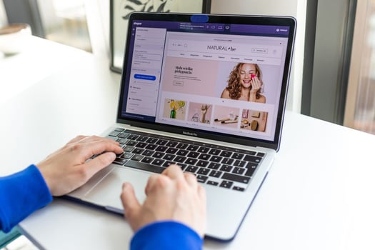 Hands editing a Shopify beauty store website on laptop for global localized payment setup with Antom
