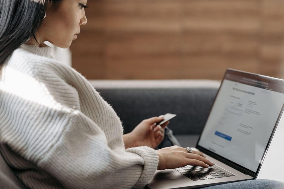 Woman in a white sweater entering card details into a laptop
